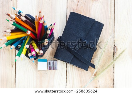 Note book and color pencils on wooden background - vintage effect style pictures