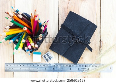 Note book and color pencils on wooden background - vintage effect style pictures