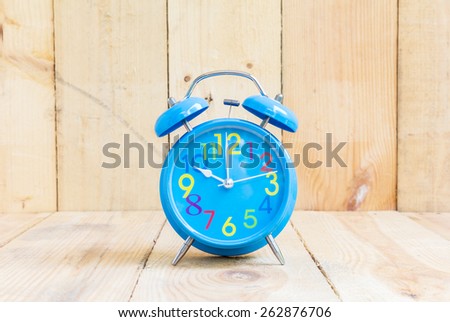 Alarm Clock isolated on white, in blue, showing ten o\'clock on wood