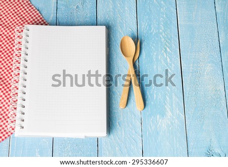 Notebook with wooden spoon on blue wood table