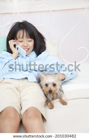 Girl speaking on the mobile phone while hugging Yorkshire Terrier dog