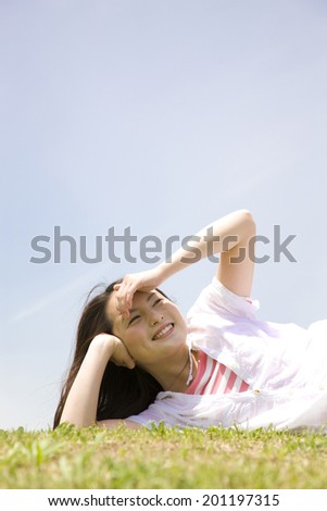 The woman looking at the sky while rolling on the grass