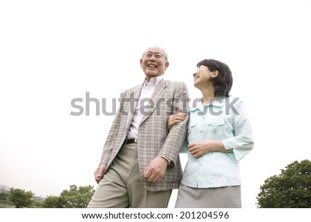 The elderly couple walking down the river bed with their arms folded