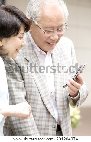 The elderly couple checking the mail of mobile phone in the city