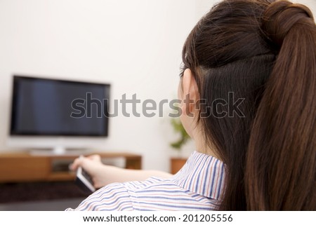 The woman trying to change the channel of the TV