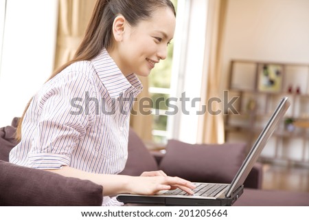 The woman operating the laptop on the sofa