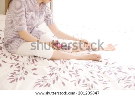 The woman holding a mobile phone on the bed