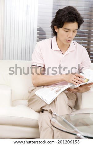 The man reading a magazine on the sofa
