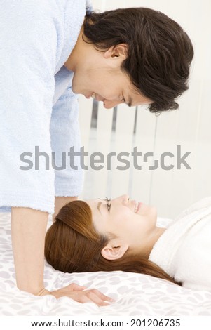 The couple in dressing gowns staring at each other on the bed