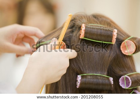 The hand of the hairdresser permming the hair of a woman