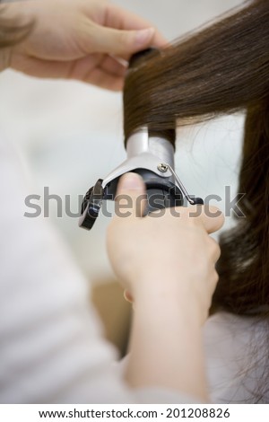 The woman receiving tongs service by a hairdresser