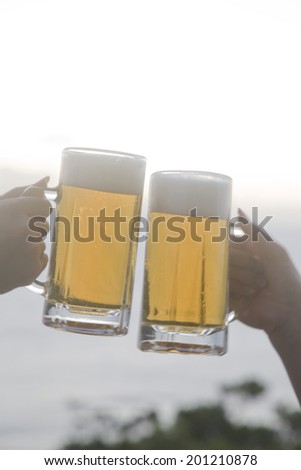 The hands of two women making a toast with beers
