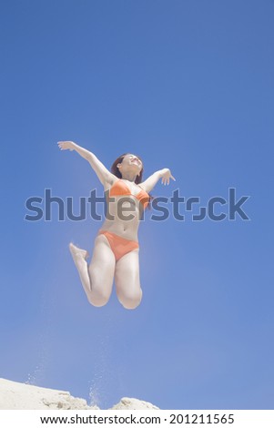 The woman with a swimming suit jumping on the beach