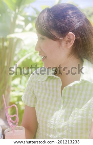 The woman chatting with friends over a cup of juice at a cafe surrounded by fresh green