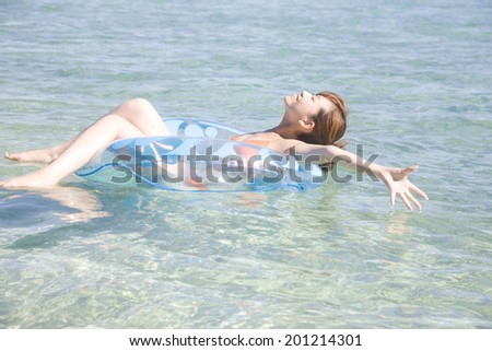 The swimsuit woman swimming in the sea with a swimming tube