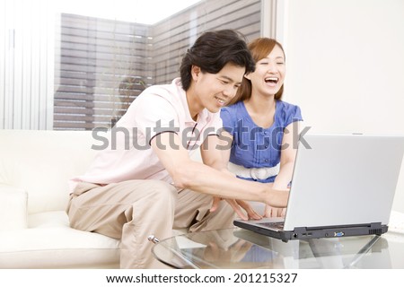 The couple operating the laptop on the sofa