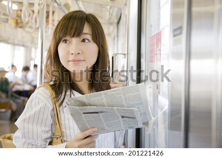The woman reading a newspaper on the train