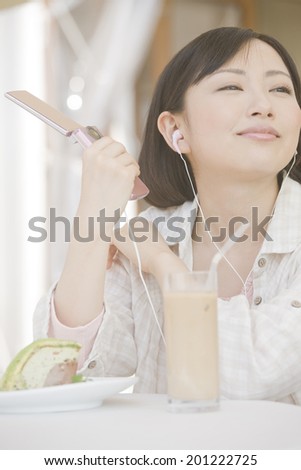 The woman listens to music while drinking tea in open cafe