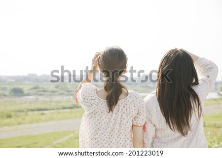 The rear view of two women standing on dry riverbed