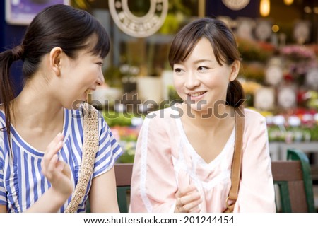 Two talking women sitt on a bench in town