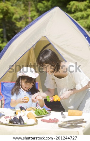 Mother and daughter inserting the ingredients to barbecue skewers