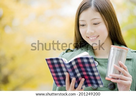 The woman reads a book while having a drink