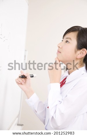 A middle school girl thinking about the answer to the problems written on the whiteboard