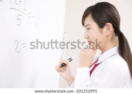 A middle school girl thinking about the answer to the problems written on the whiteboard