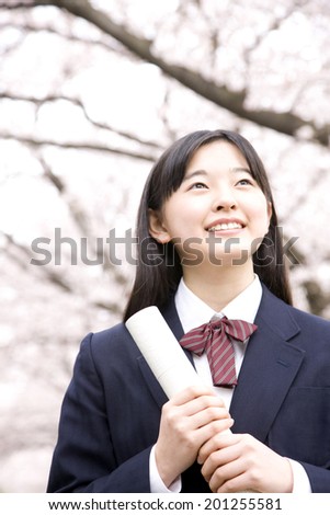 A middle school girl smiling with holding a tube of diploma