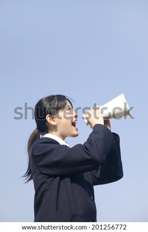 A middle school girl making a loud sound through a megaphone