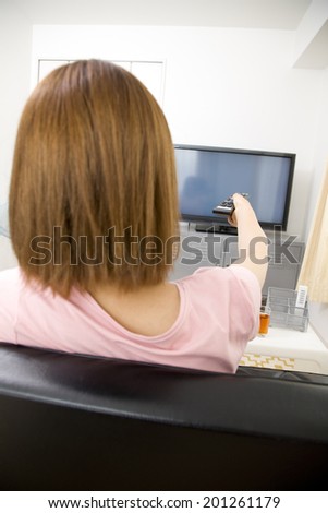 Back figure of a woman turning on the TV