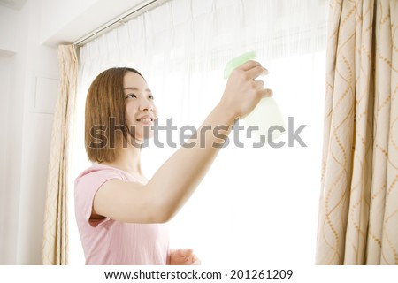 Woman spraying a deaodorant spray on the curtain