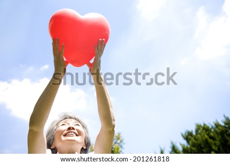 A middle-age woman holding a heart-shaped balloons