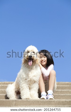 smiling girl sitting on stairs with Golden Doodle