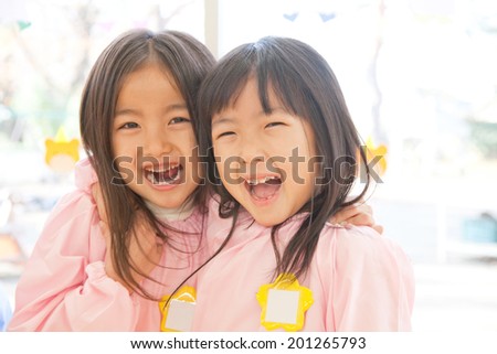 Two kindergarteners putting arms around each other\'s shoulders