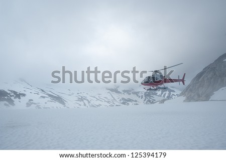 Helicopter landing on top of the mountain covered with snow. Alaska