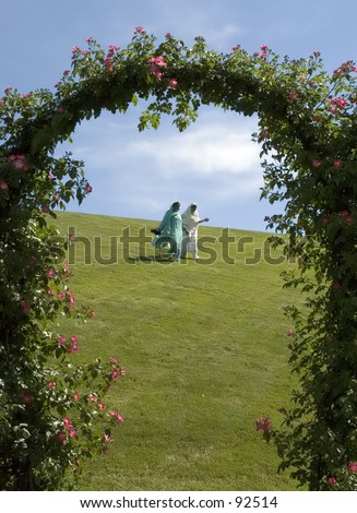 Two indian ladies on the green field through the rose arch