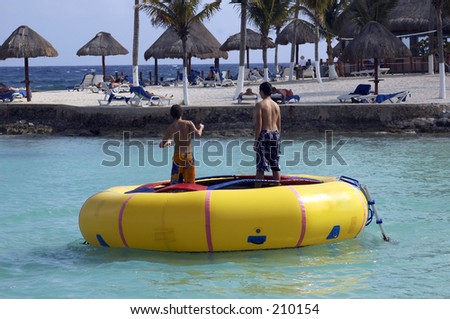 Two boys on water trampoline on the morning beach