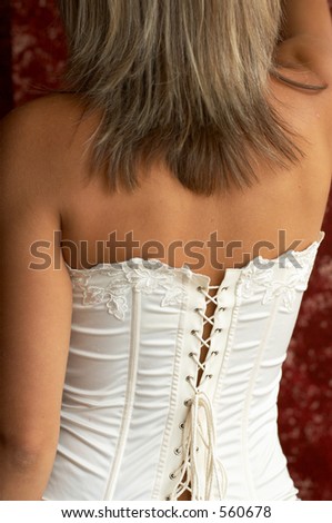 female in corset, standing back to the camera