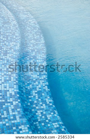steps into the blue pool at the tropical resort. Vertical orientation