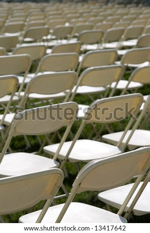 rows of empty white folding chairs on the loan