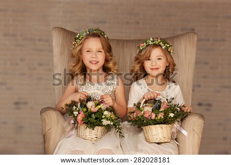 two little bridesmaid sitting in a chair with bouquets