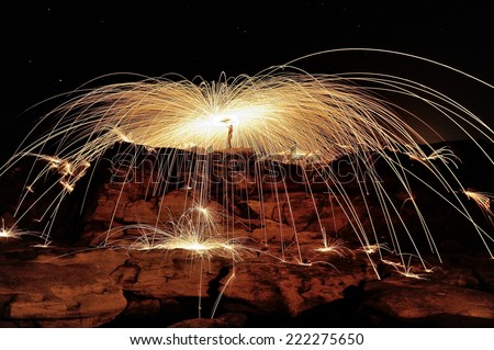 Fire spinning by a rock cave made with burning steel wool and long exposure.