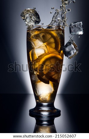 Ice tea glass with splash of tea and ice cube isolated on light background