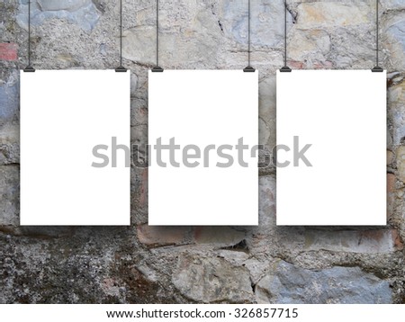 Three hanged paper sheets with clips on medieval stone wall background