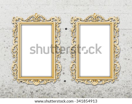 Two golden baroque frames on grey concrete wall background