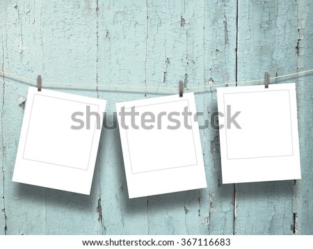 Close-up of three hanged polaroid photo frames with pegs on aqua weathered wooden boards background