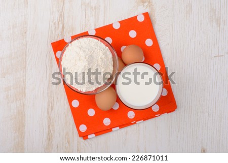 flour, milk, eggs, baking ingredients on a red tablecloth