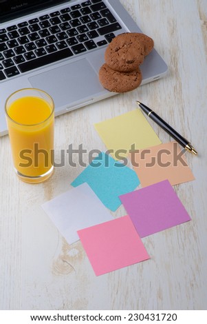 Laptop with glass of juice, sticky note paper with cookies on old wooden table