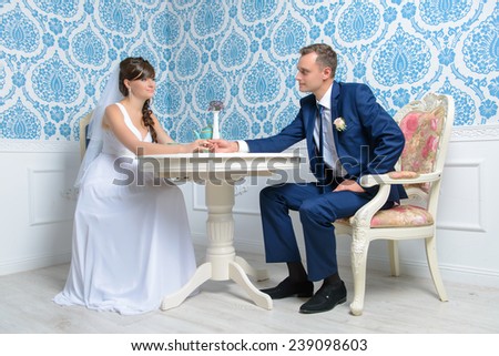 Beautiful bride and groom sitting at the table in the studio